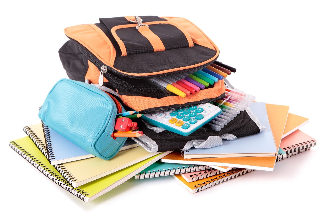 a pile of school supplies including a backpack, pencil case and notebooks